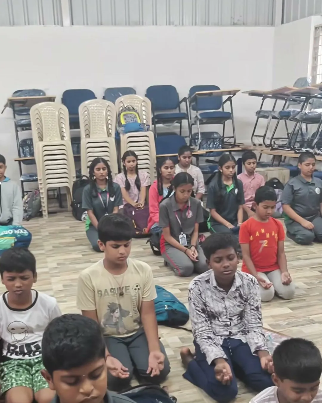 Children sitting in Vajrasana with their hands resting in their laps and eyes closed