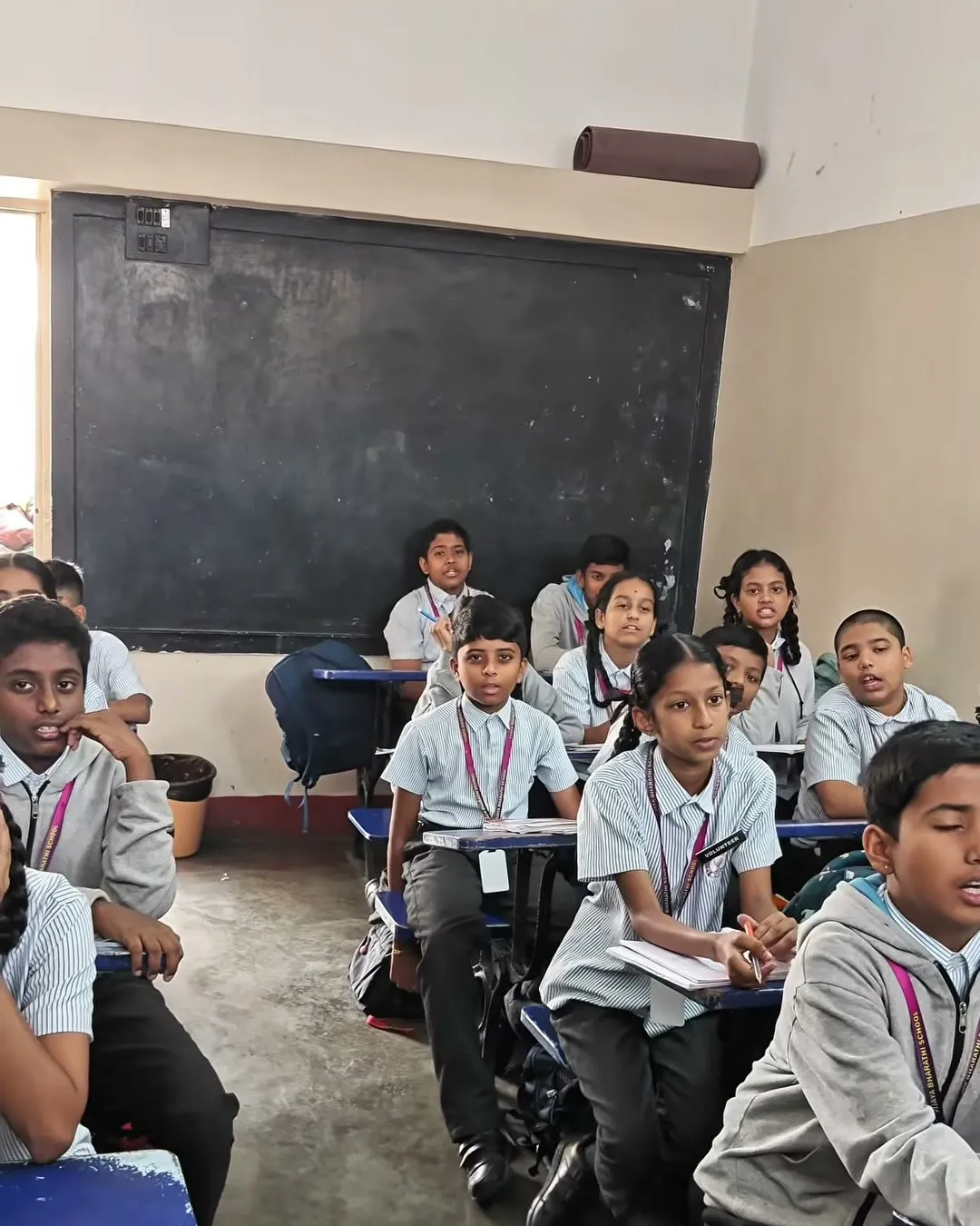 Students in uniform at their desks in a classroom with a blackboard at the front
