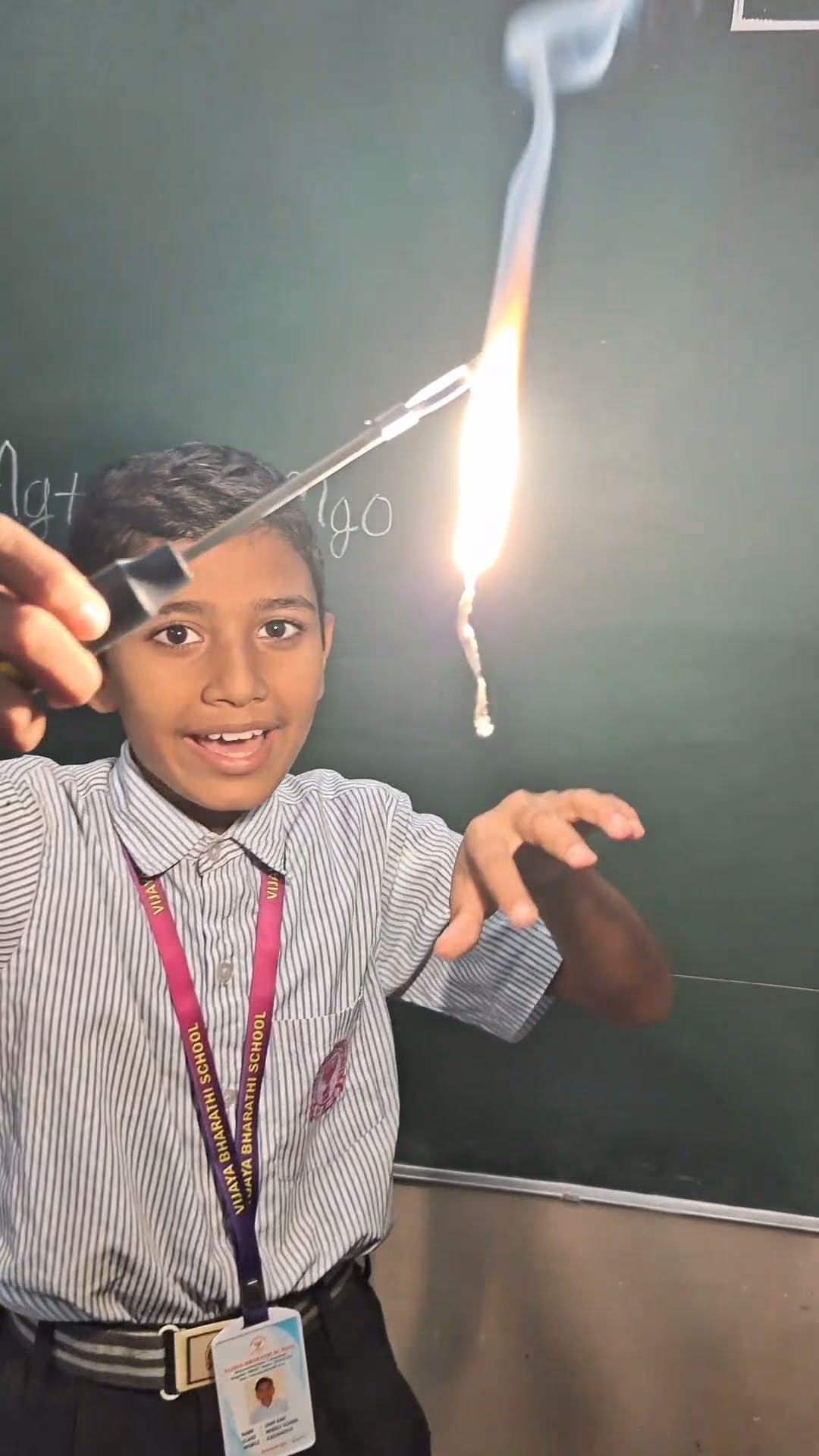 A student holding a burning magnesium ribbon in a chemistry lesson