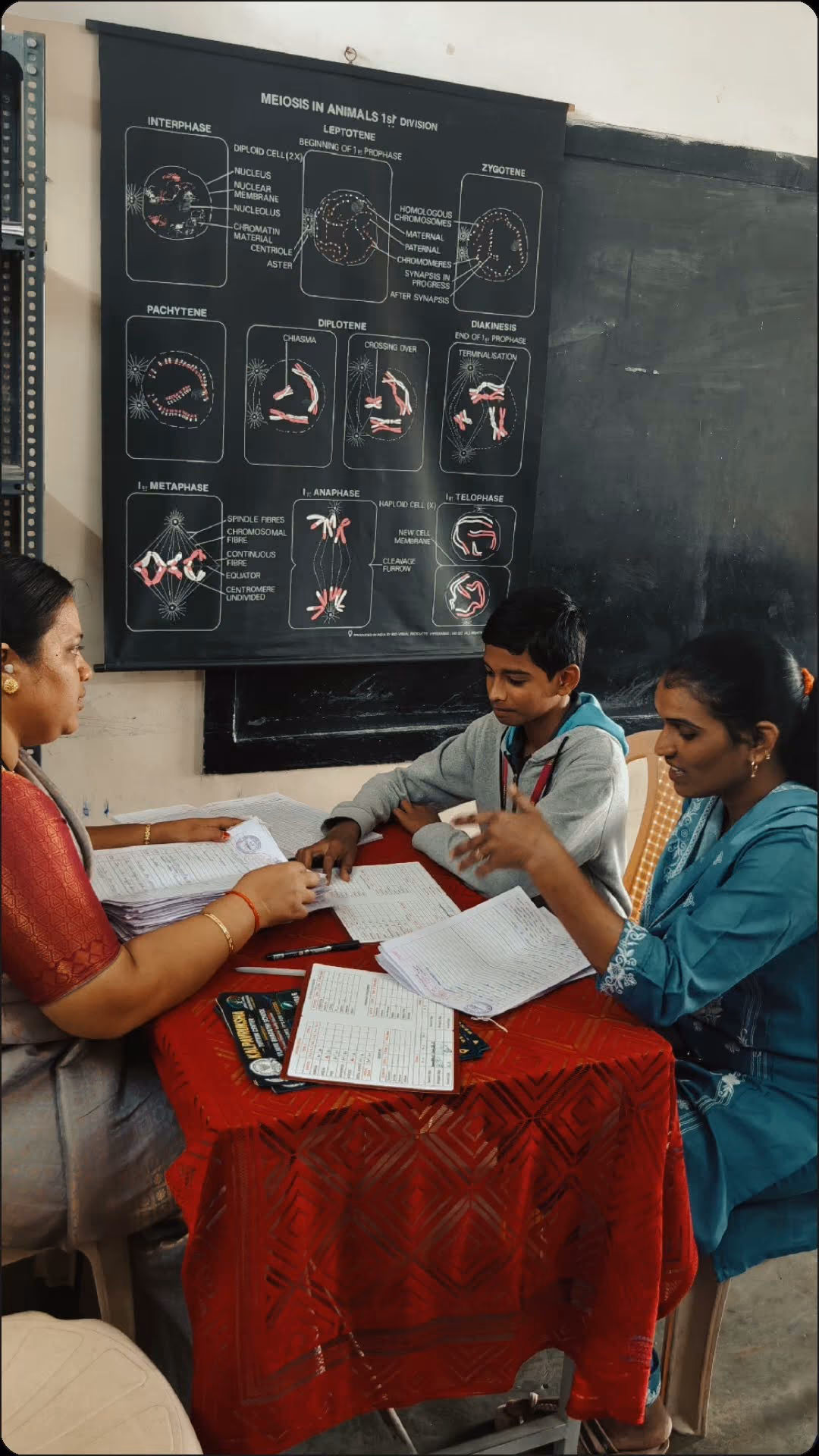 A teacher with a student and parent at a parent-teacher meeting